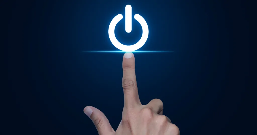 An index finger reaching for a lit power button, indicating the finger is about to turn something off